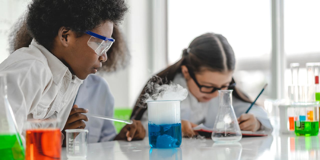 Elementary school aged students working on a science project wearing safety glasses.