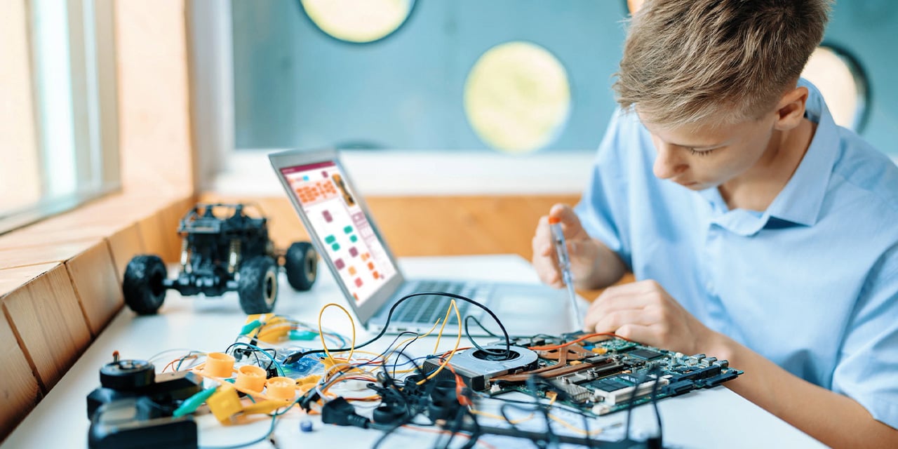 Student at a desk working on a robotics projects. 