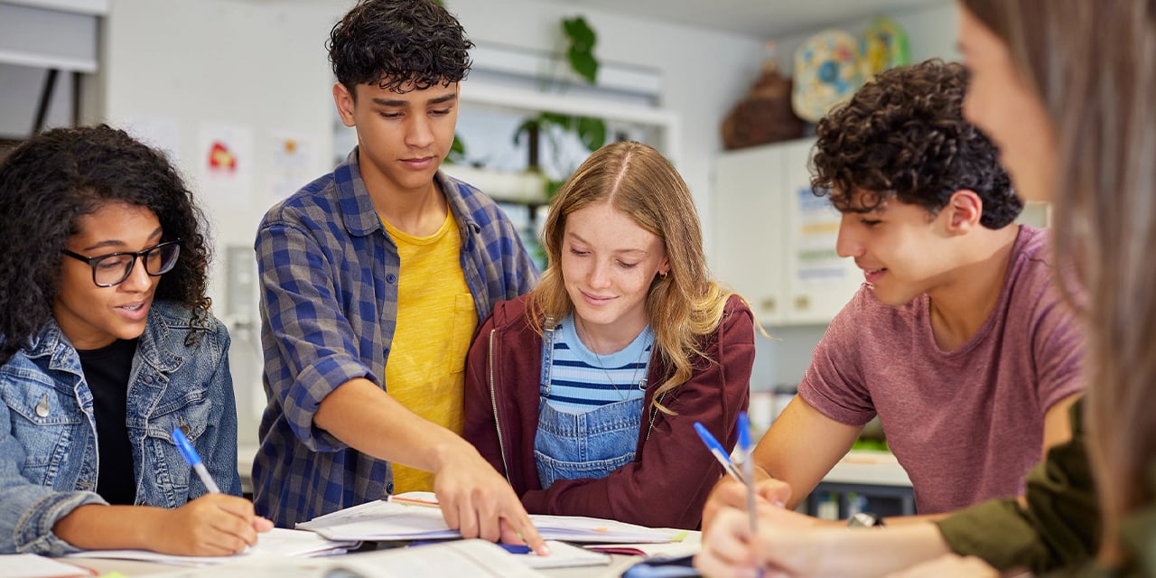 High school students working on a project together at a table in a classroom.