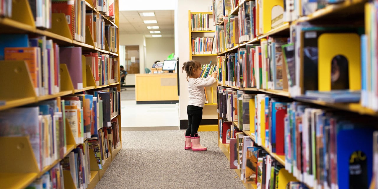 Child looking at books in a library.