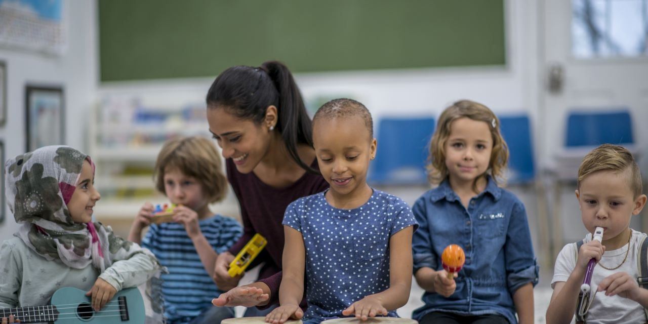 Children exploring musical instruments with a teacher.
