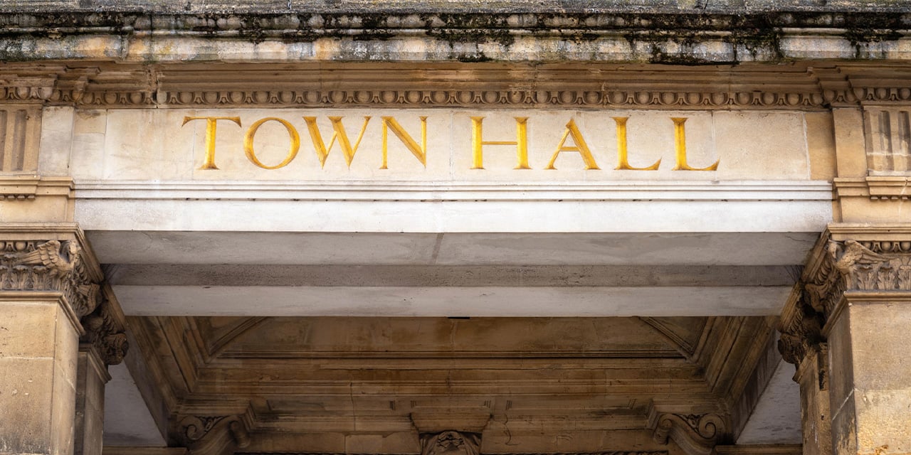 Exterior image of a stone building with the words town hall on the front.