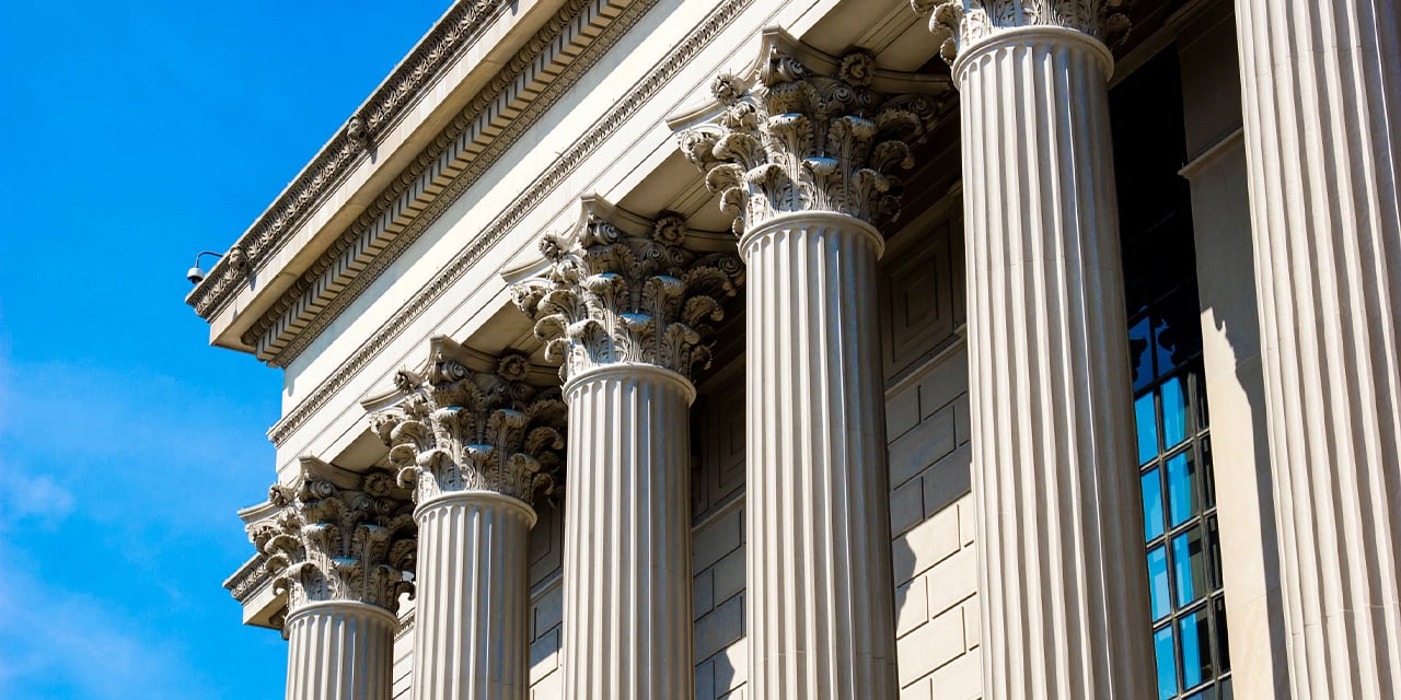 Exterior view of a historic building with stone pillars and large glass windows.