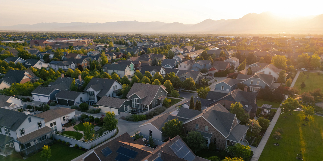 Arial view of a neighborhood at sunset with mountains in the background.