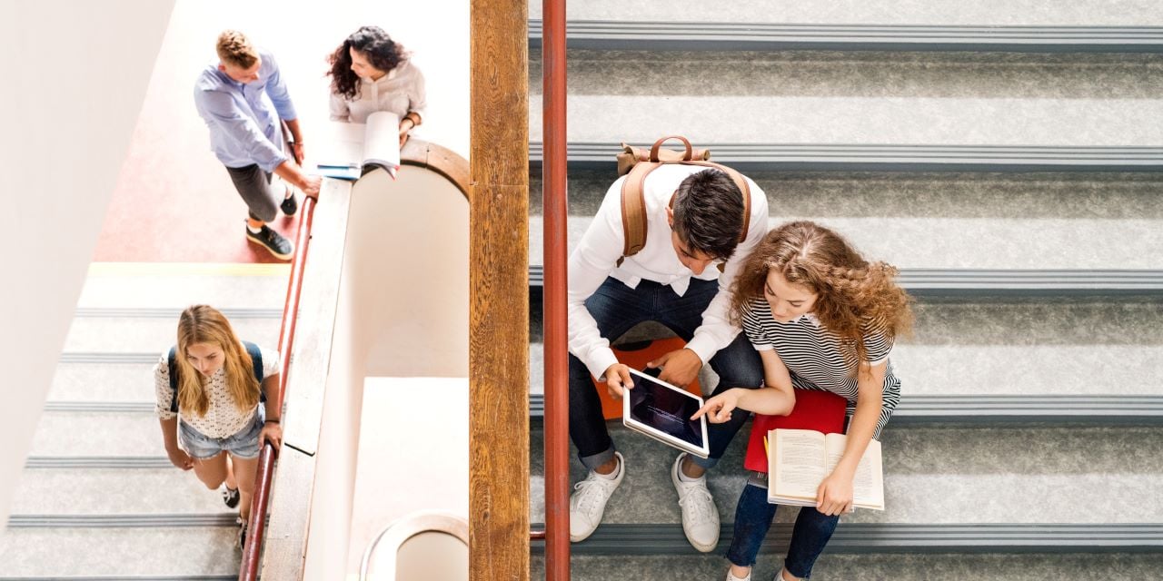 High school students sitting and standing on stairs while talking.