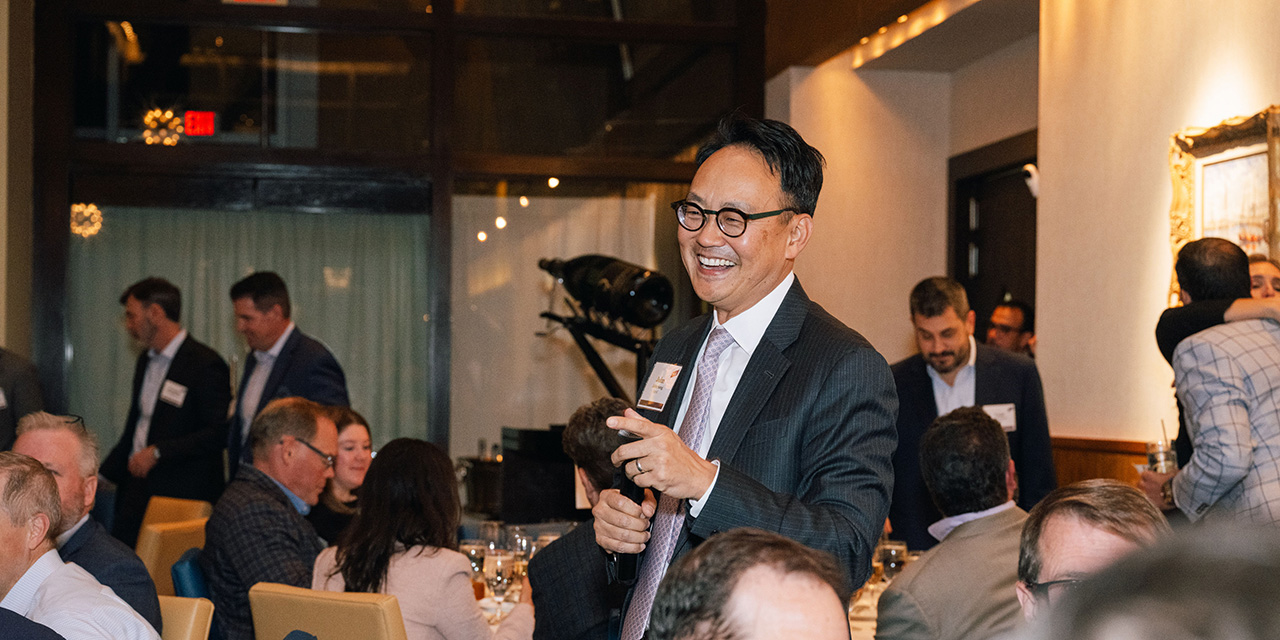 Man smiling while talking to others during a dinner reception.