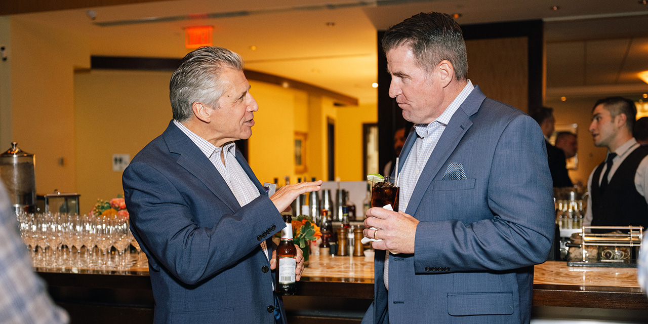Two men having a discussion during a dinner reception.